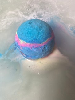 A blue bath bomb in the water, fizzing.