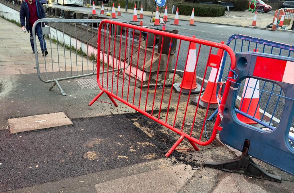 Barriers and cones blocking a crossing. One of the barriers is stuck out into the pathway. 